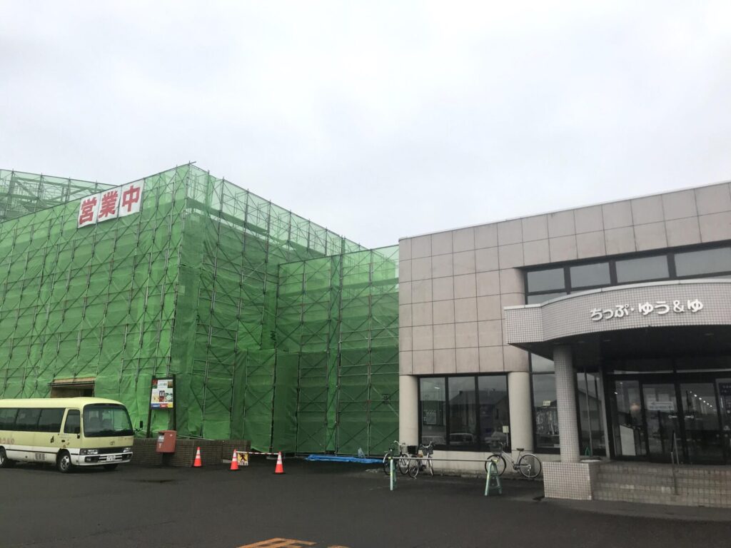 緑の足場に覆われたちっぷ・ゆう＆ゆ、営業中の看板あり