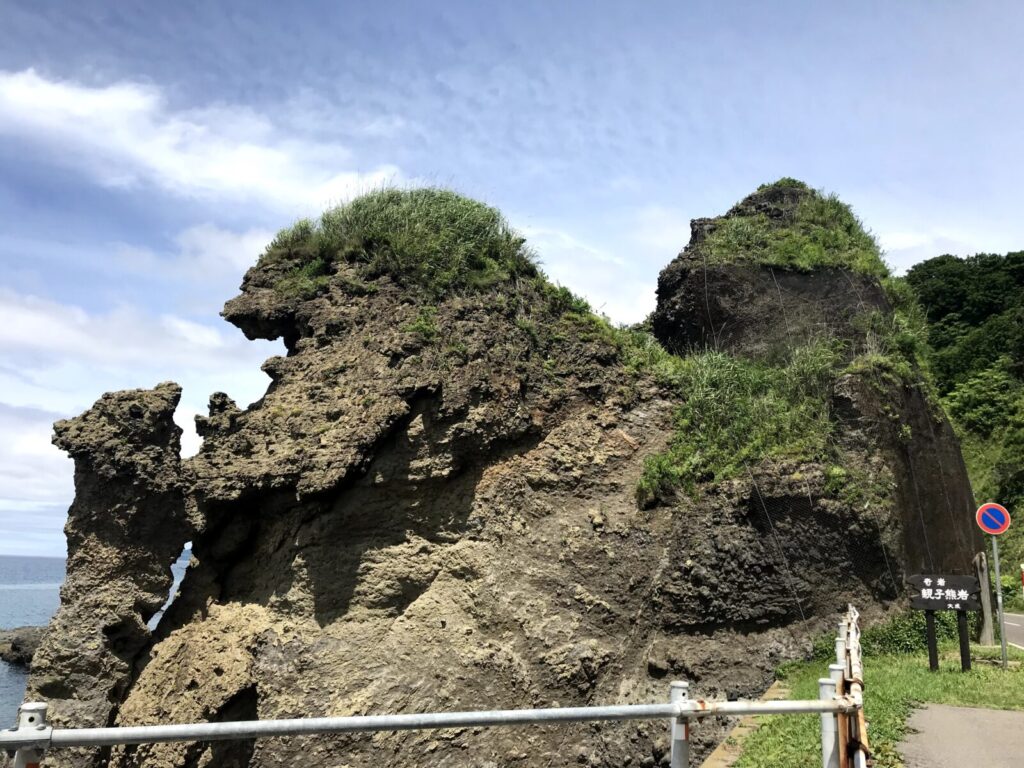 海沿いに立つ親子熊岩の全体像と周辺の遊歩道