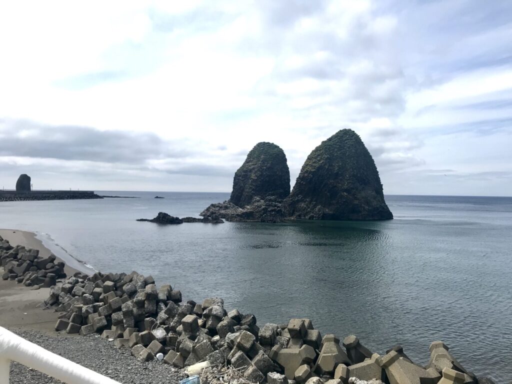 穏やかな海に浮かぶ三本杉岩（夫婦岩）の風景