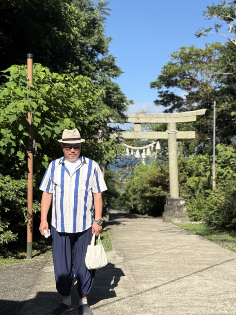 鳥居を背にした男性が神社の参道を歩く様子