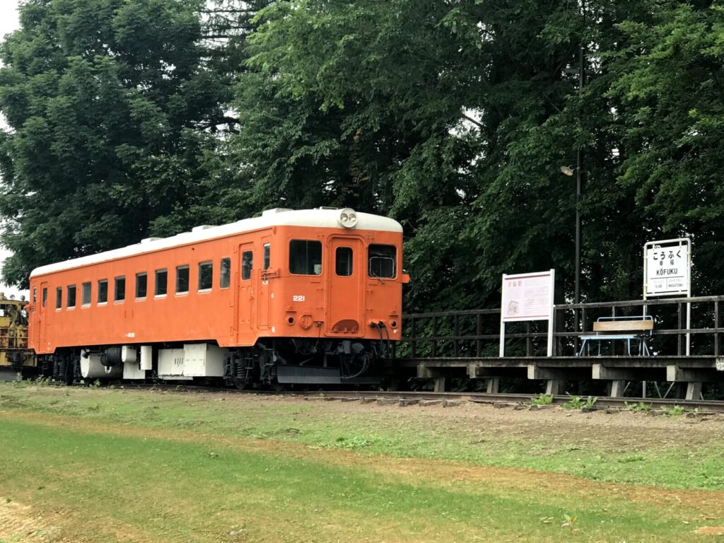 幸福駅のホームに停車する保存車両と「こうふく駅」の駅名標の風景