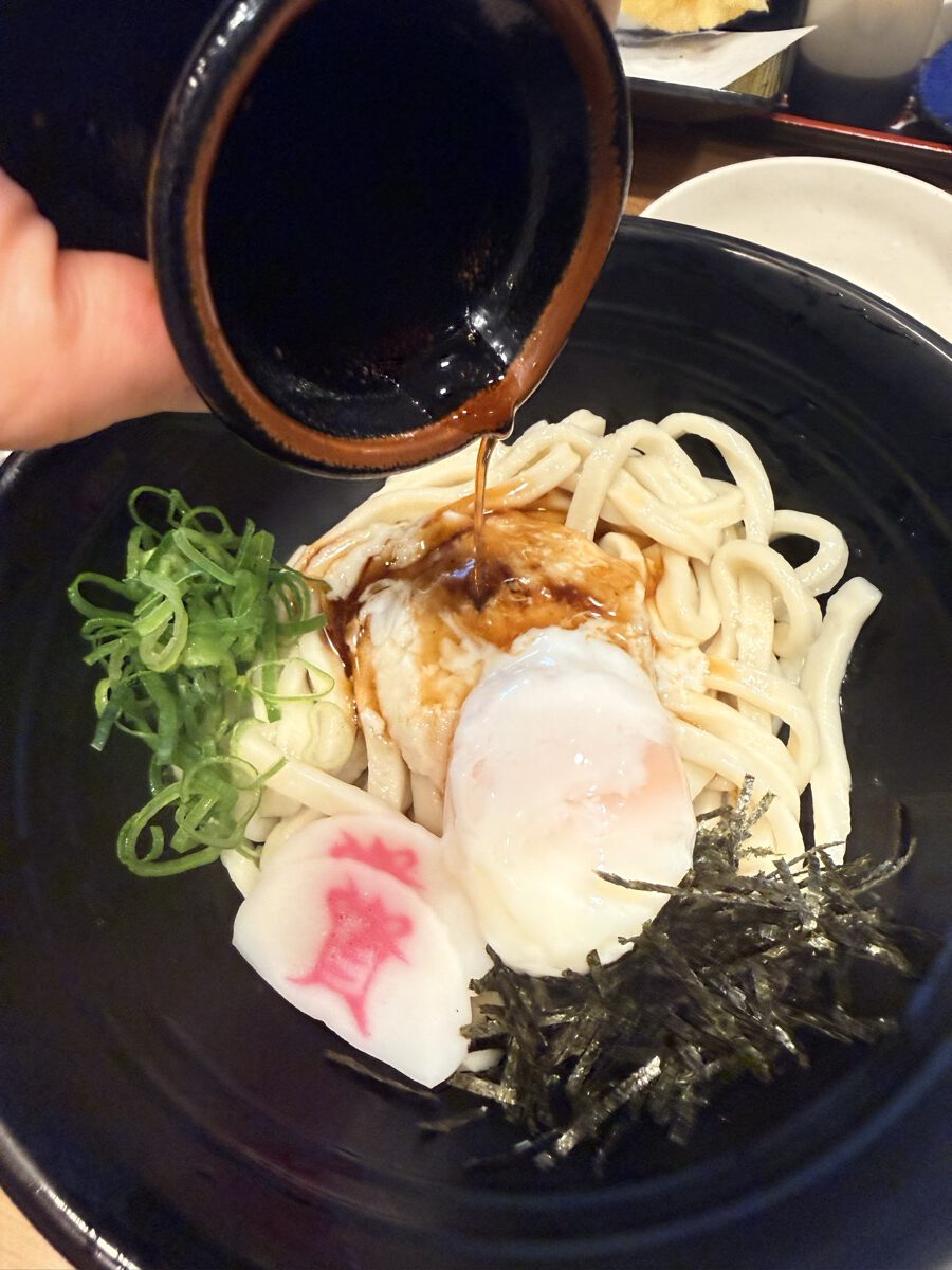 資さんうどんの冷うどんにざるつゆをかけている瞬間